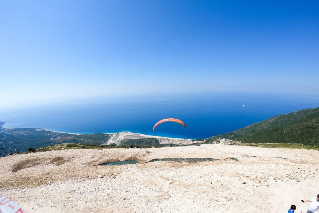 A paraglider flying over the Llogara Pass, offering breathtaking views of the Albanian Riviera.