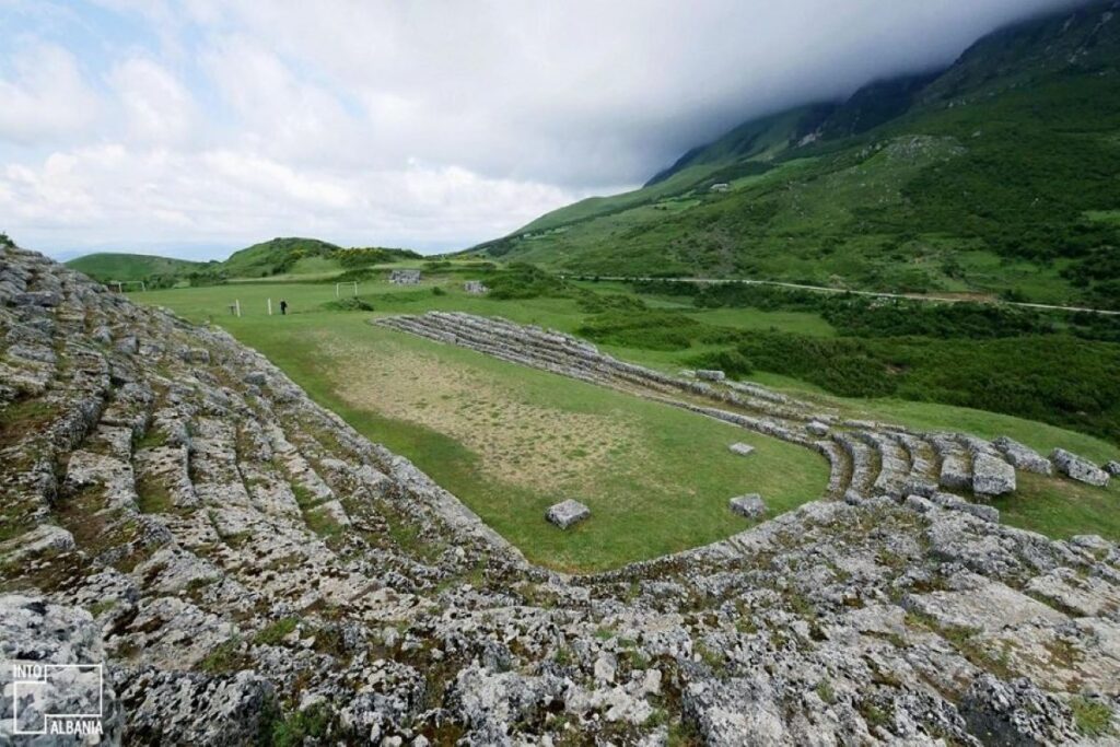 The ancient stadium at Amantia, nestled in the hills of southern Albania under a bright blue sky.