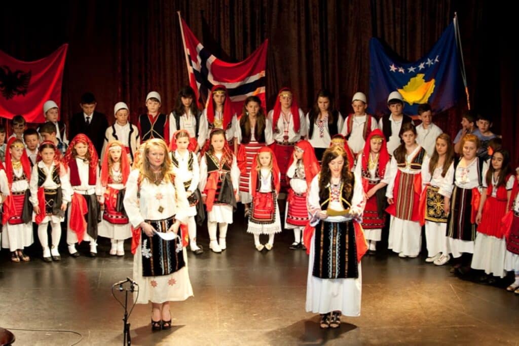 Dancers in traditional Central Albanian attire performing a folk dance at a festival.