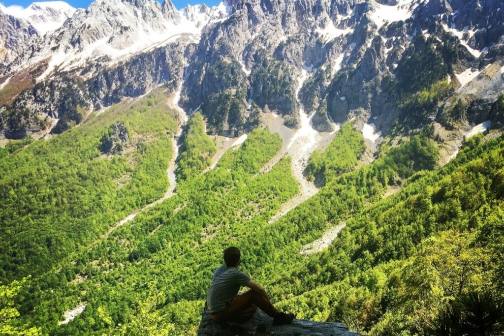 A hiker at Valbona Pass, surrounded by the towering peaks of the Albanian Alps in North Albania.