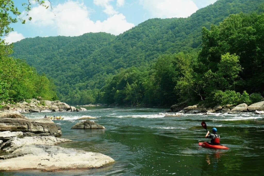 A kayaker exploring the serene waters of the Erzen River in Central Albania, surrounded by lush nature.