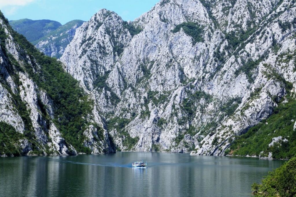 The Lake Koman Ferry navigating through dramatic gorges surrounded by lush greenery in Albania.