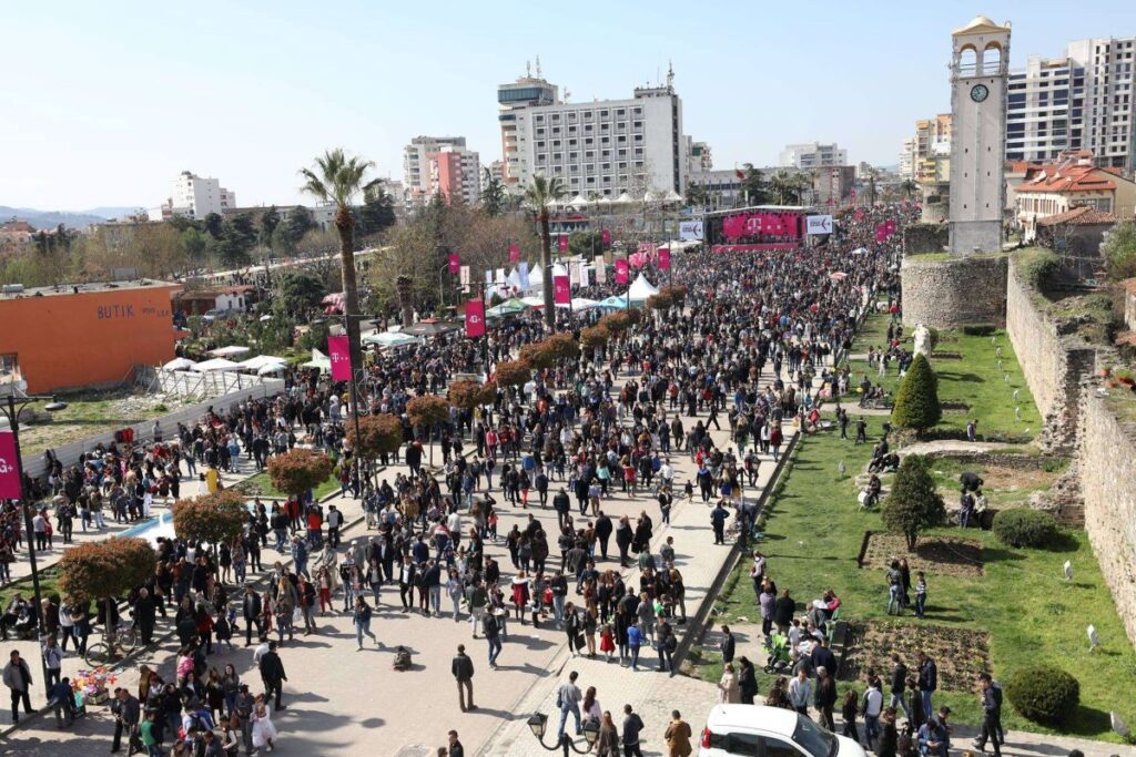 Crowds celebrating Dita e Verës in Elbasan, with colorful decorations and traditional dances.