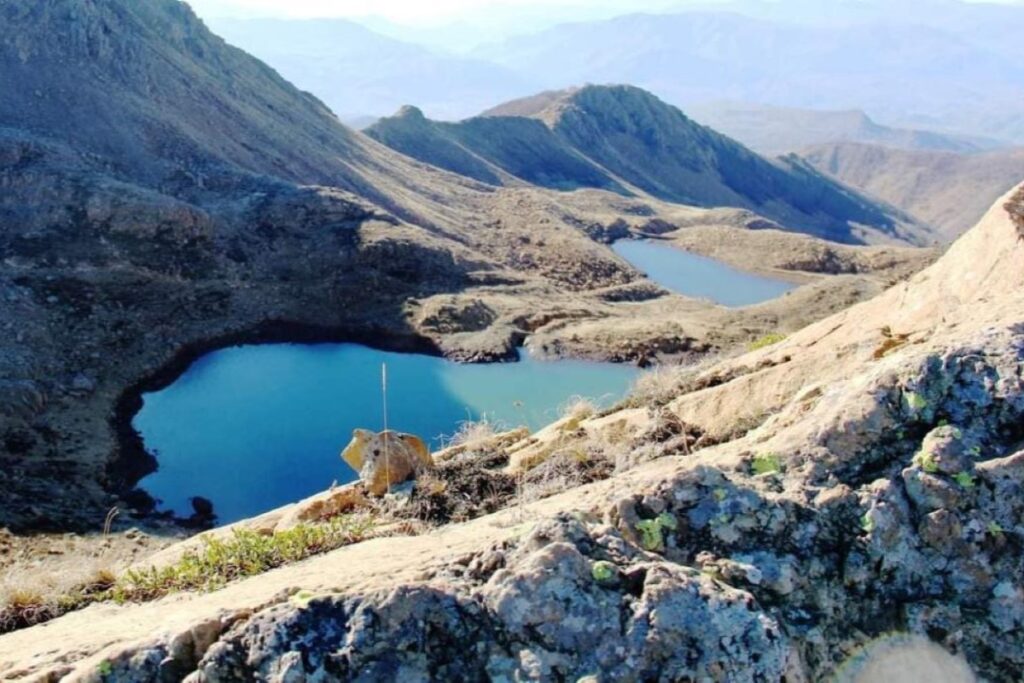 Dragostunja Lakes with calm waters reflecting the lush green hills and trees surrounding them.