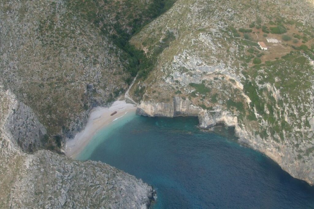 Grama Bay on the Karaburun Peninsula, with turquoise waters and rocky cliffs under a clear sky.