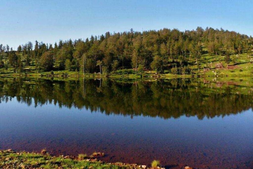 One of the Seven Lakes of Lura, with calm waters reflecting forests and mountains.