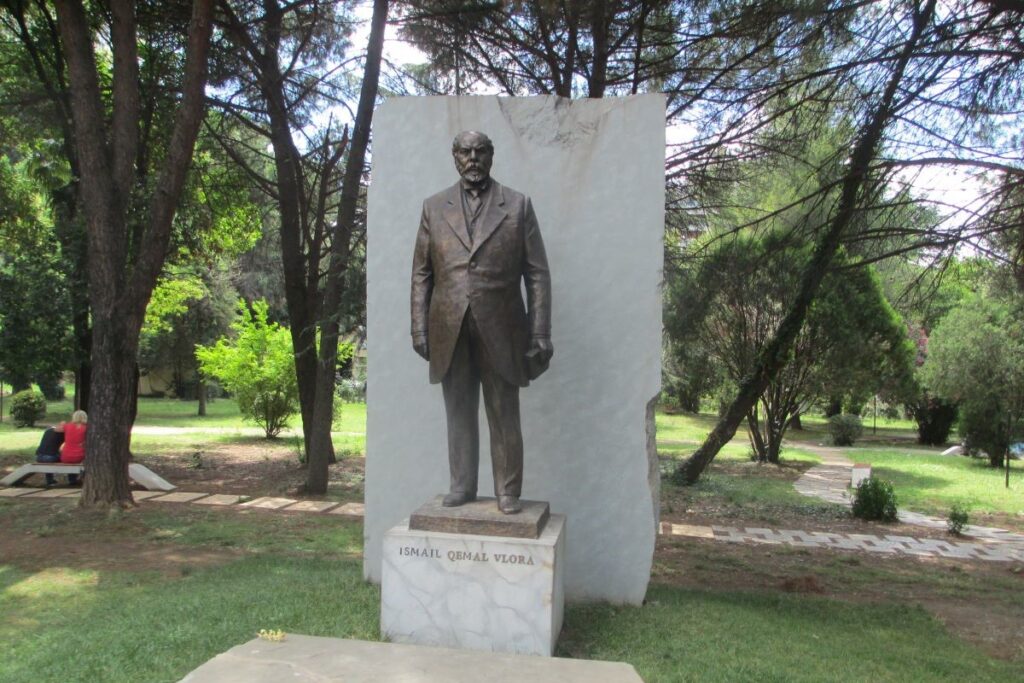 The statue of Ismail Qemali in Vlorë’s Independence Square, surrounded by the vibrant Albanian flag.