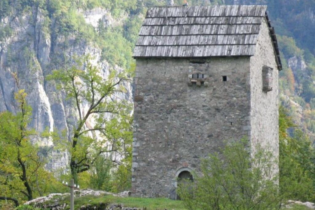 Stone tower of Kulla e Ngujimit surrounded by lush greenery and rugged mountain scenery in northern Albania