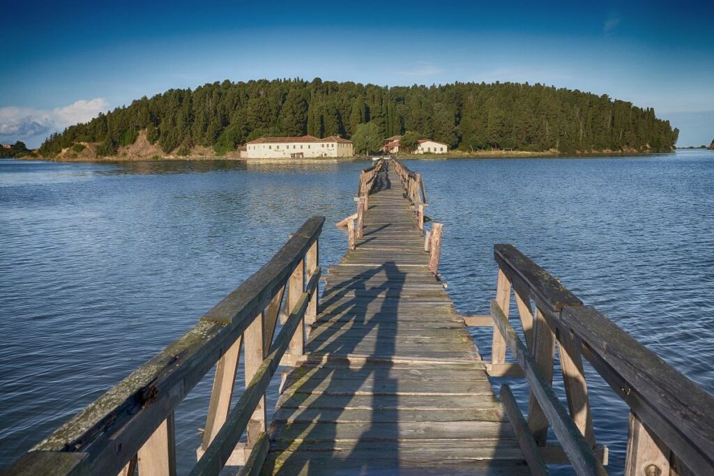 The wooden bridge to Zvernec Island in Narta Lagoon, with the monastery surrounded by pine trees.