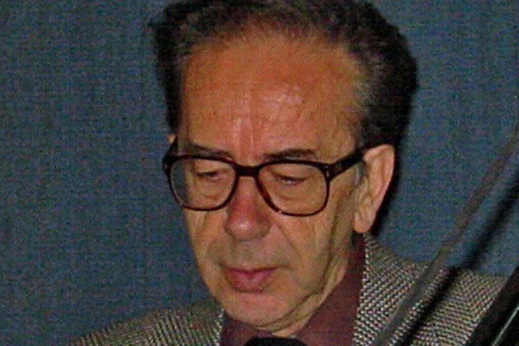 Ismail Kadare reading a book during a public appearance.